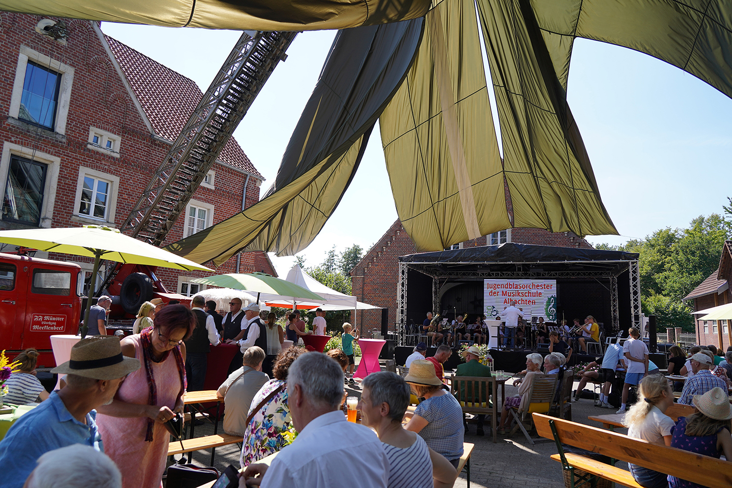 Blick in den einladend gestalteten Hof Schulze Blasum: ein großer Fallschirm und zahlreiche Schirme und Pavillons sorgen für Schatten und ein gemütliches Ambiente